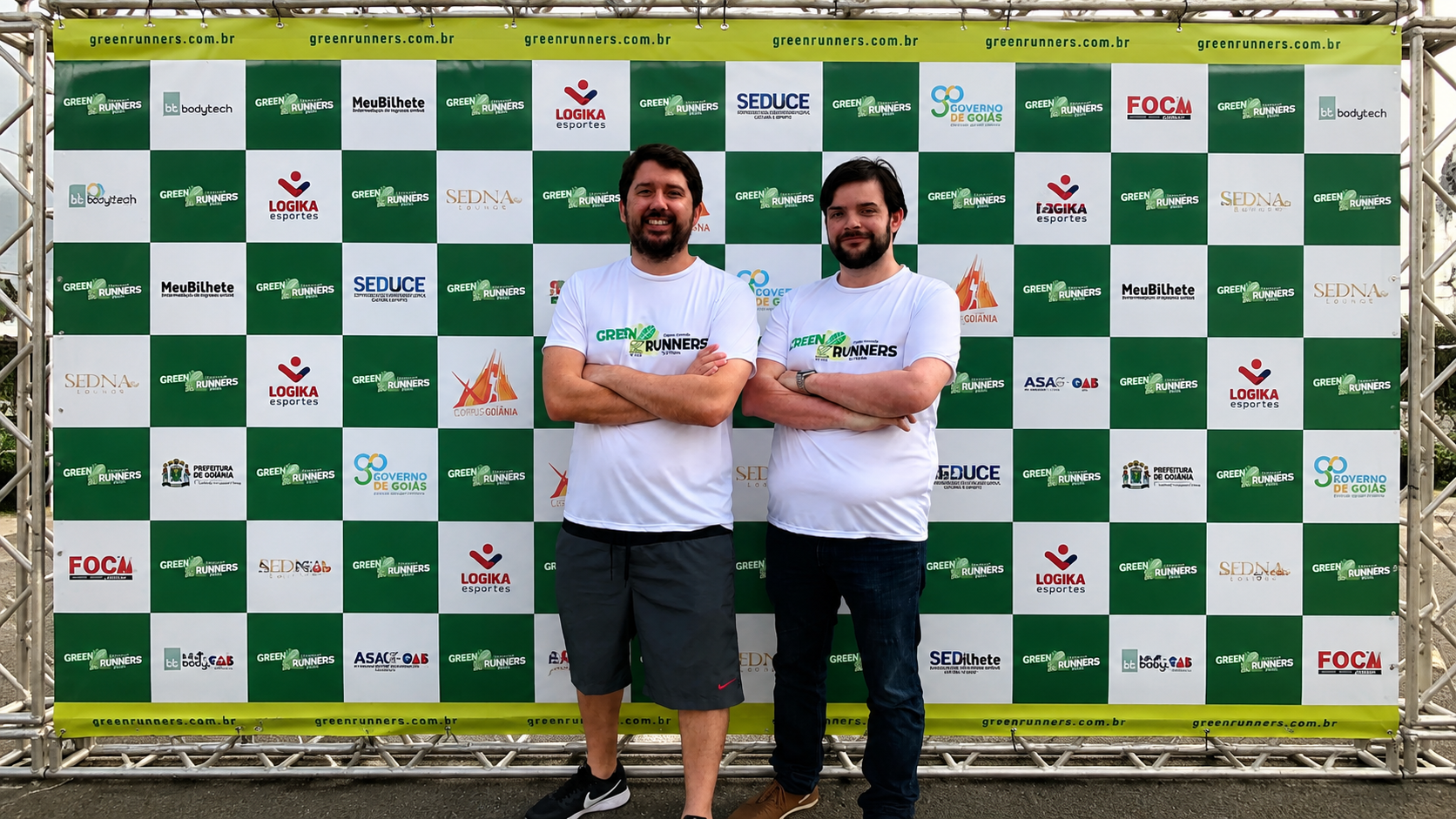 Sócios da LOGIKA Esportes em evento esportivo, com painel de patrocinadores ao fundo